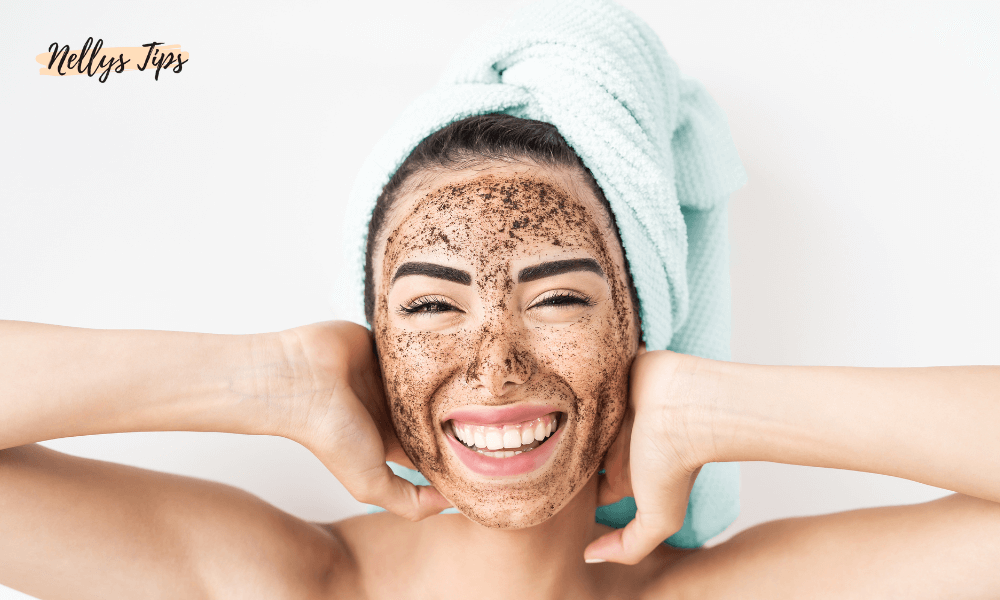 Leende kvinna med handduk på huvudet och exfolierande ansiktsmask, glad efter hudvårdsrutin.