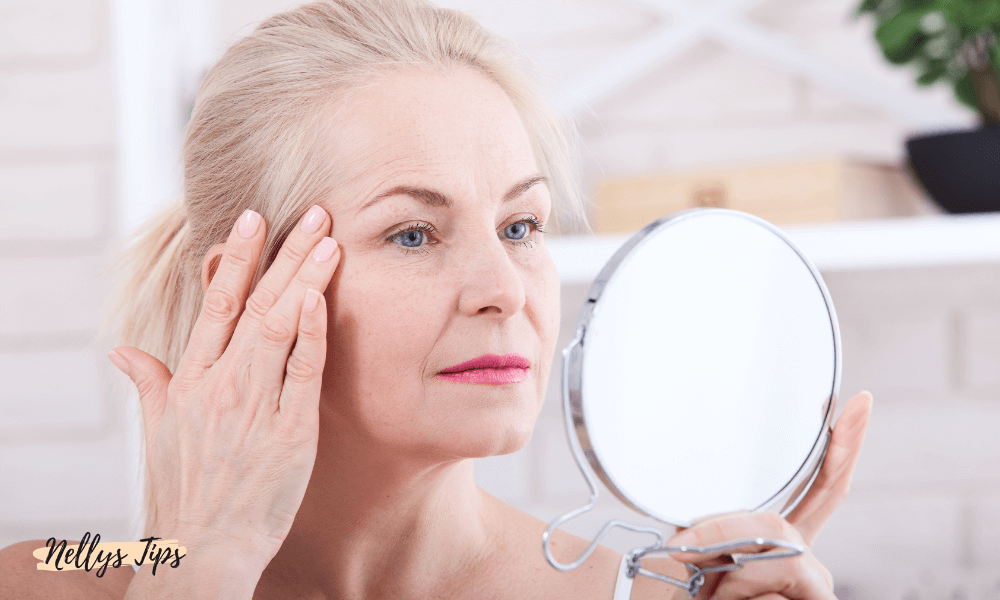 Äldre kvinna granskar sin hud i spegel, med naturlig makeup och vårdad hy.