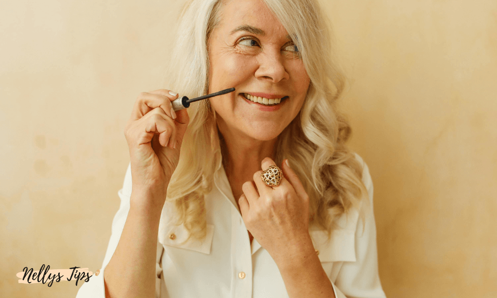Leende kvinna applicerar mascara, ett perfekt exempel på smink för mogen hud och fransar.
