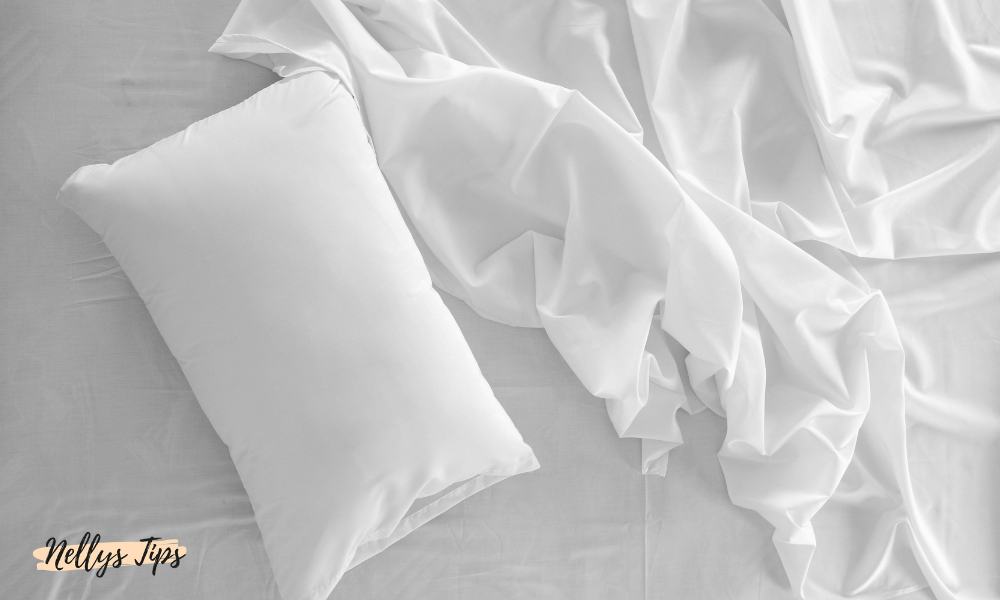 Vita sängkläder med kudde och lakan i silkeslen textil för lyxig sovkomfort.