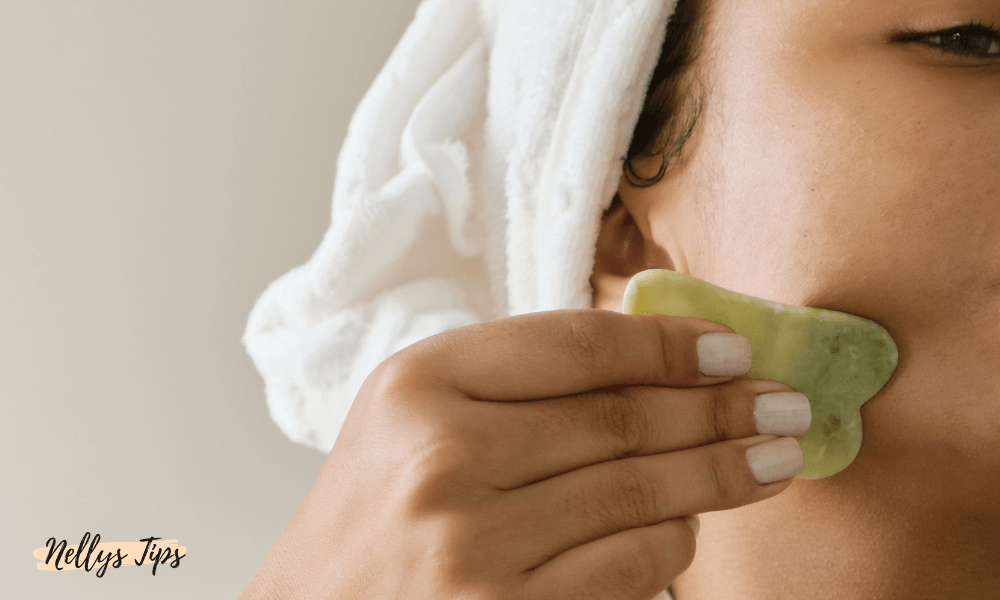 Kvinna använder grön gua sha-sten i ansiktsmassage för att förbättra blodcirkulation och hudton.