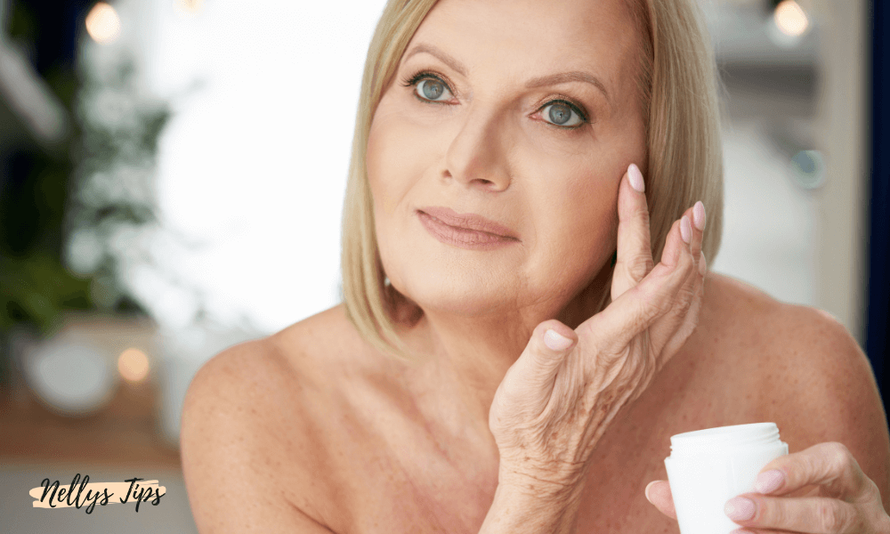 Leende mogen kvinna applicerar anti-age kräm under ögat med fingertopparna.