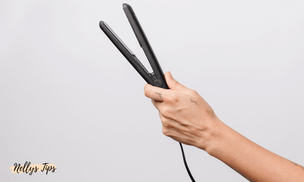 Hand som håller i en svart BaByliss plattång redo för användning.