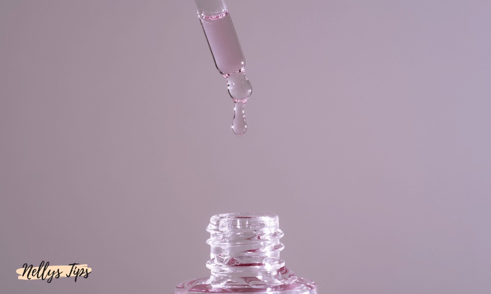 Pipett med rosa serum droppar vätska ner i en glasflaska, fokus på återfuktning.