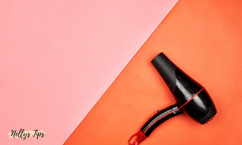 Kompakt hårfön med röd detalj fotograferad mot färgglad rosa-orange bakgrund.