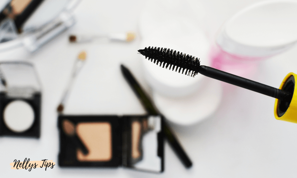 Närbild på mascaraborste med sminkprodukter i bakgrunden – fokus på fransvolym och makeupdetaljer
