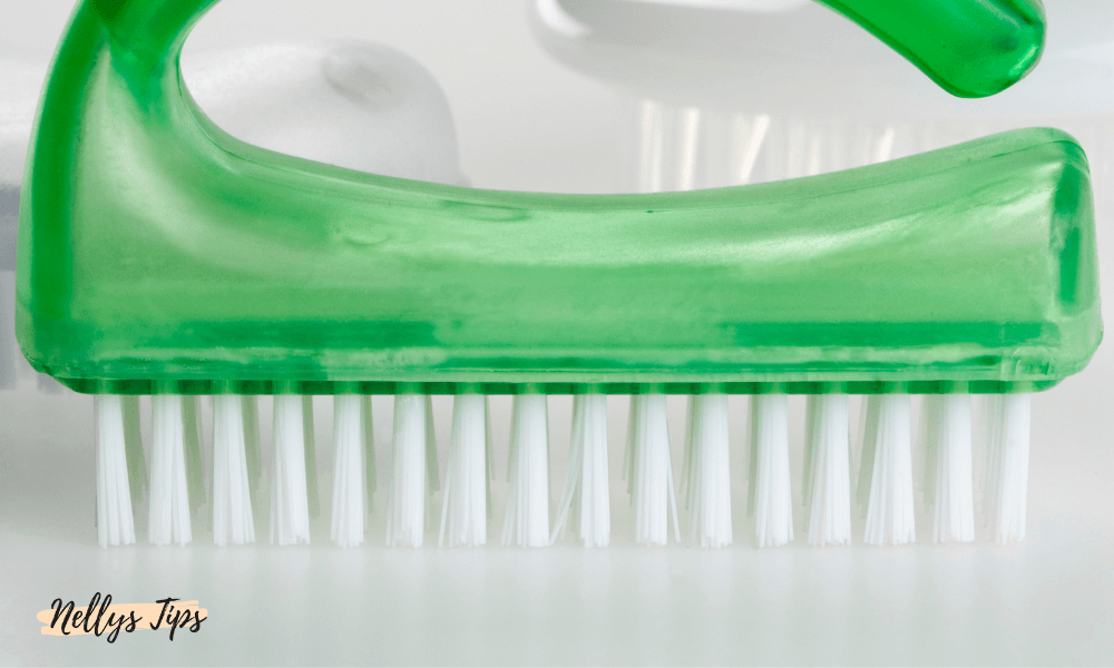 Grön nagelborste med plastgrepp och vita borst för effektiv rengöring av naglar och nagelband.