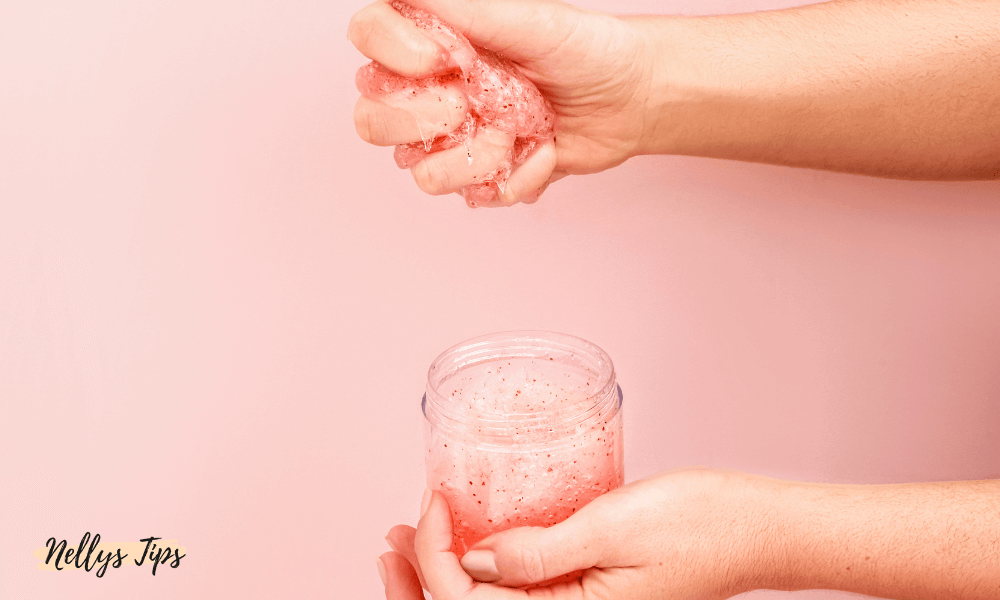 Person pressar rosa handskrubb med peelingkorn ur burk för skonsam handexfoliering