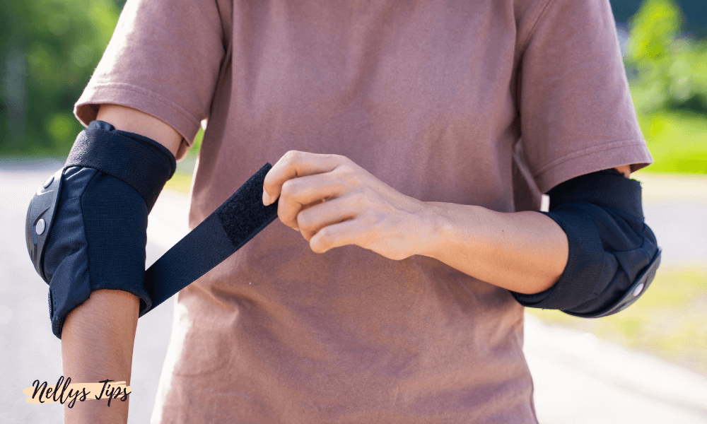 Person med armbågsskydd drar åt kardborreband för extra stöd och skydd vid fysisk aktivitet.
