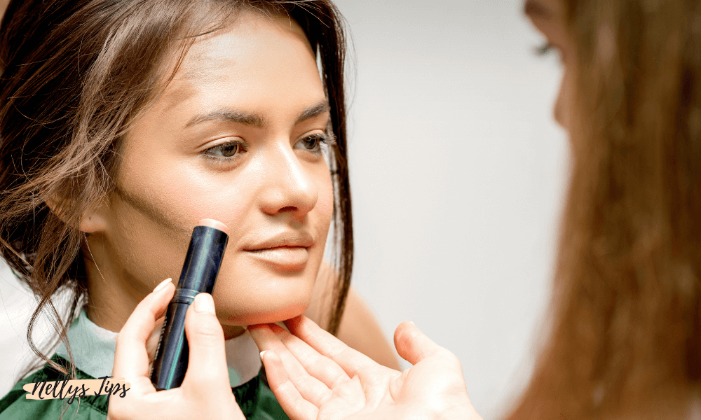 Makeupartist applicerar contourstick på kvinnas kindben med mörk stickfoundation