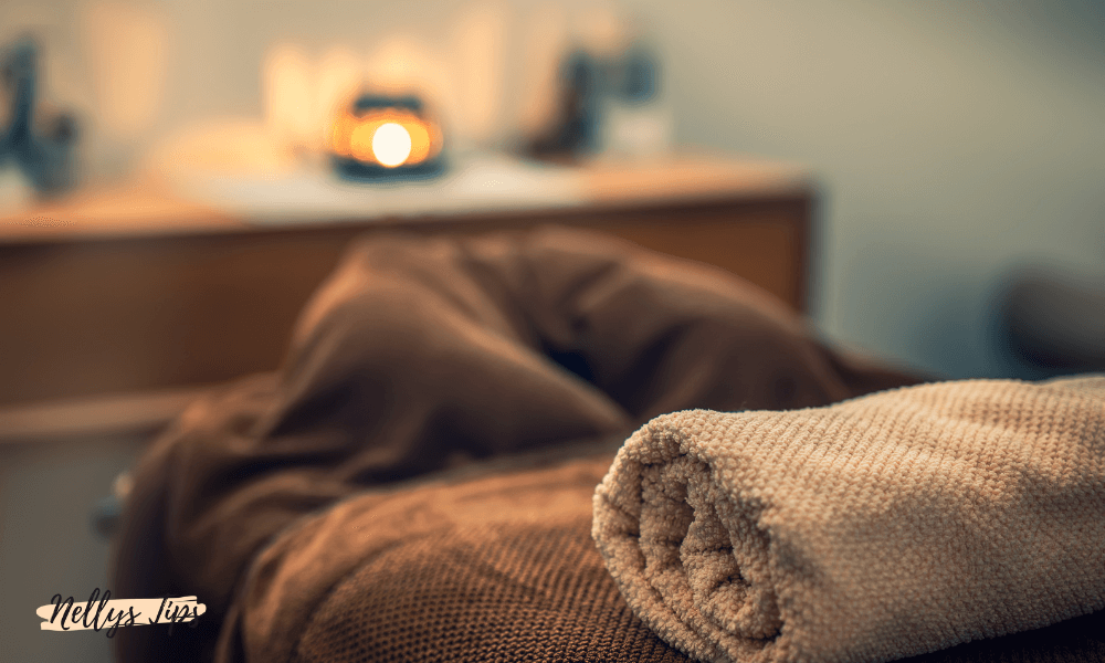 Avslappnande massagesäng med hoprullad handduk och dämpad belysning i behandlingsrum.