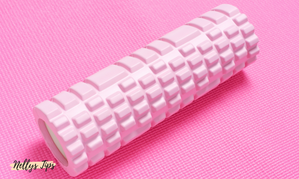 Rosa foam roller med strukturyta för djupmassage, placerad på yogamatta.