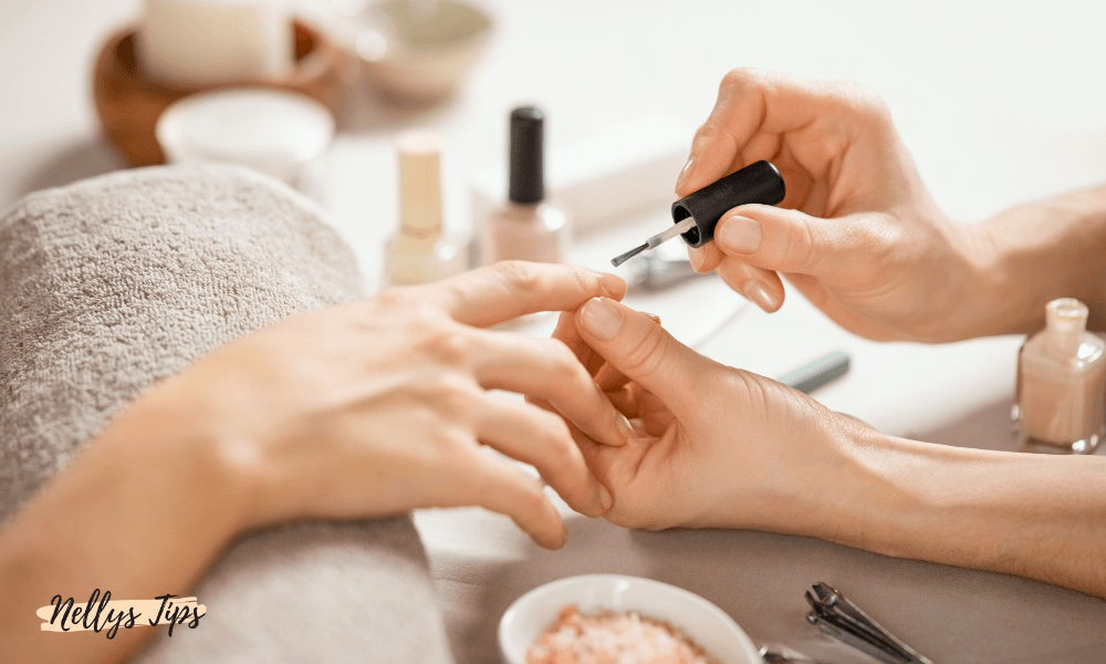 Hand får manikyr med giftfritt nagellack under professionell behandling på salong.
