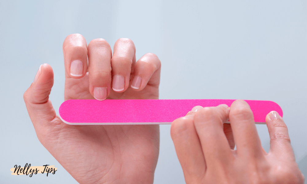 Person som filar naglarna med rosa nagelfil – vårdande manikyr för naturliga naglar