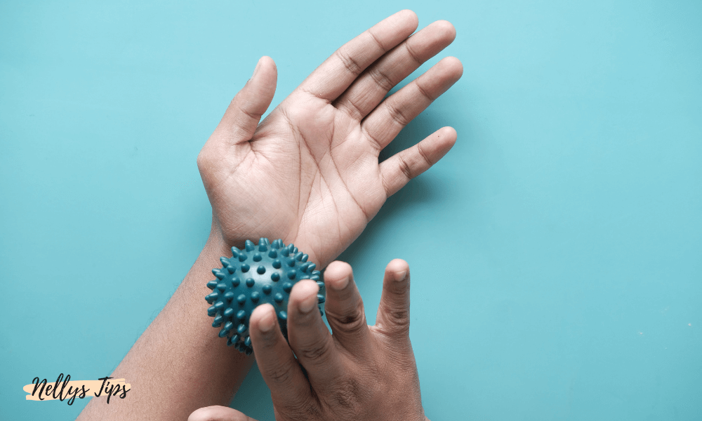 Handmassage med en blå massageboll med piggar för smärtlindring och muskelavslappning.