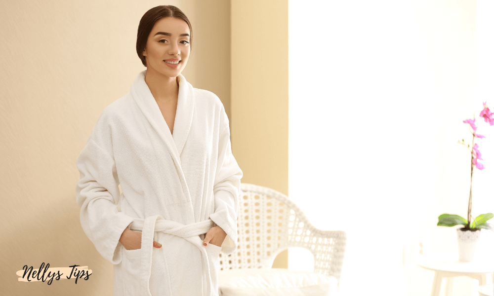 Kvinna i vit morgonrock med bälte och sjalkrage, perfekt för hemmabruk eller spa.