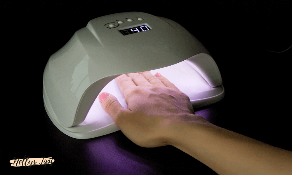 Hand torkas under UV-lampa med digital timer för att härda gellack på naglarna.