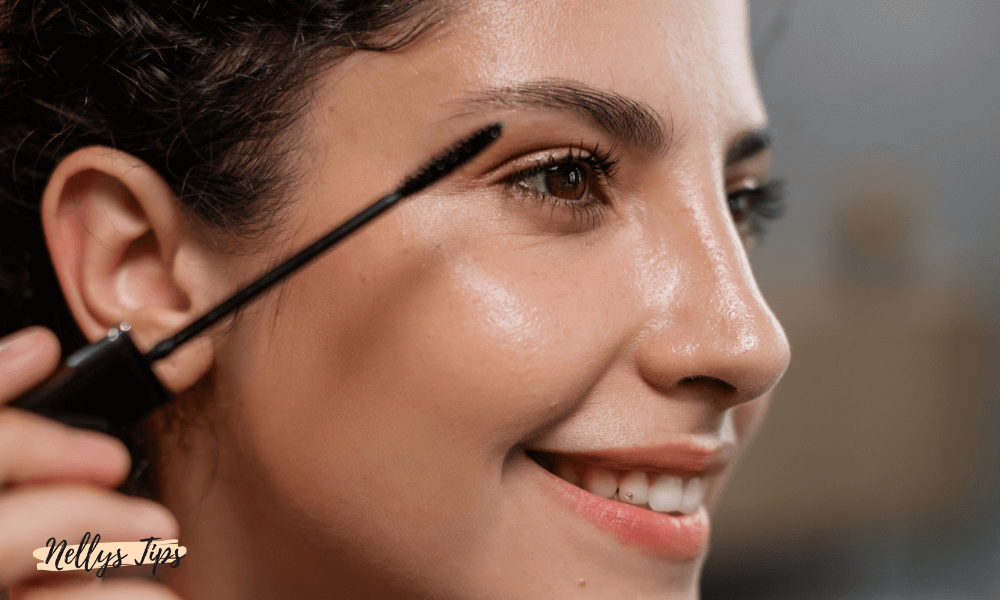 Leende kvinna applicerar mascara på övre fransarna för en naturlig och definierad look.