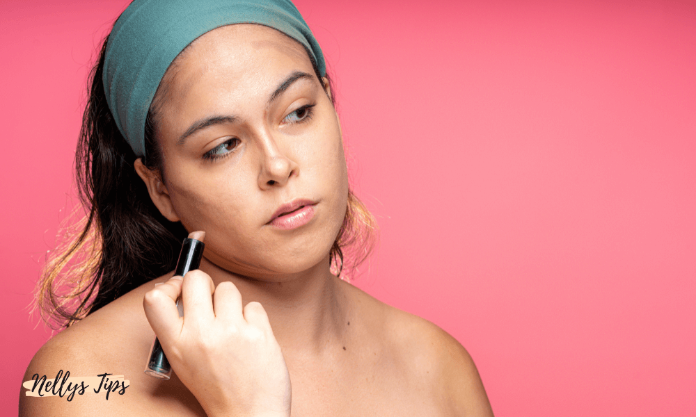 Kvinna applicerar contour stick längs käklinjen för att framhäva ansiktskonturer.