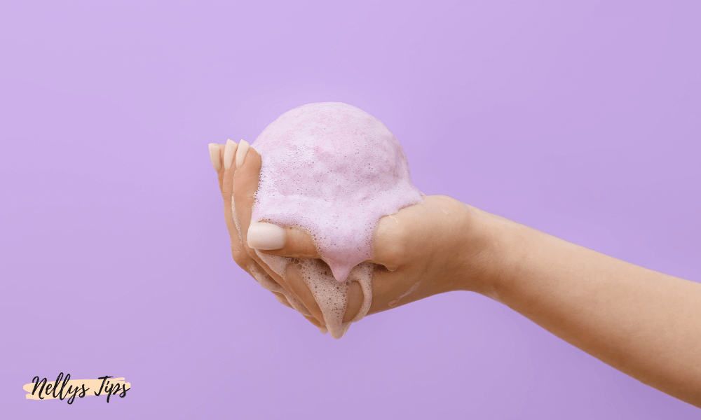 Hand med rosa lödder från färgbomb för temporär hårtoning
