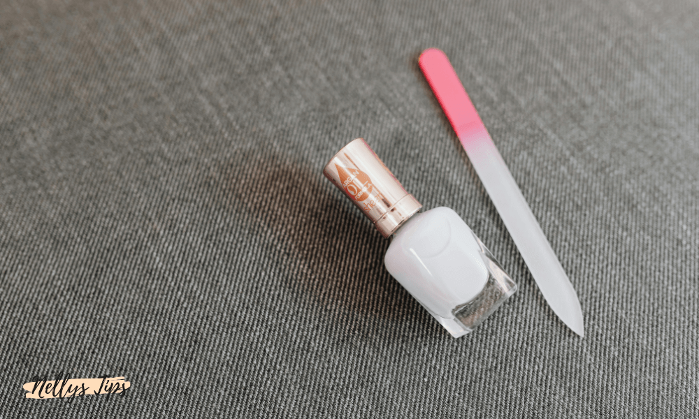 Glasnagelfil med rosa topp och vitt nagellack – stilren manikyrprodukt på tygunderlag