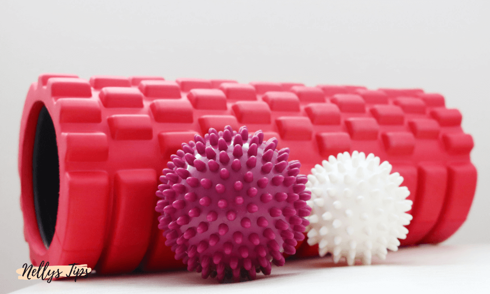 Rosa och vit massageboll med piggar bredvid en räfflad foam roller för muskelmassage.