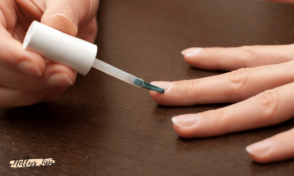 Person applicerar nagelbandsremover med pensel på fingernagel för att mjuka upp nagelband.