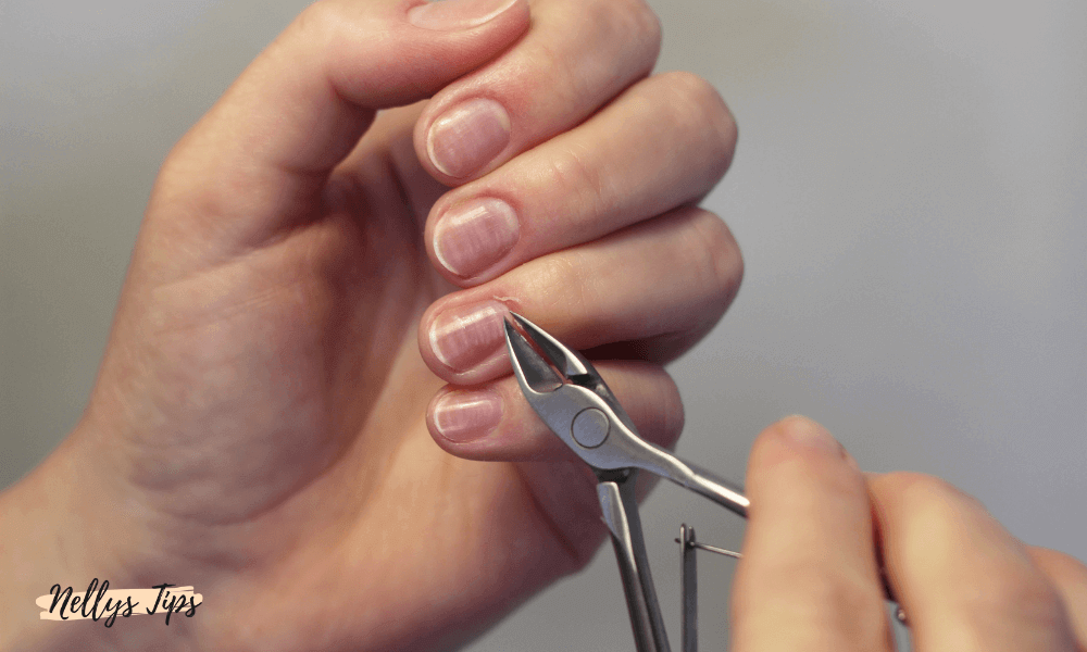 Närbild på klippning av nagelband med tång – visar praktisk användning vid manikyr hemma.