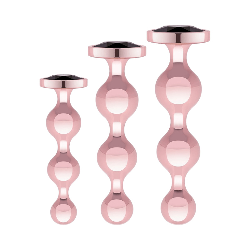 Set med tre roséguld metallbuttpluggar med kulformad design och juveldekor