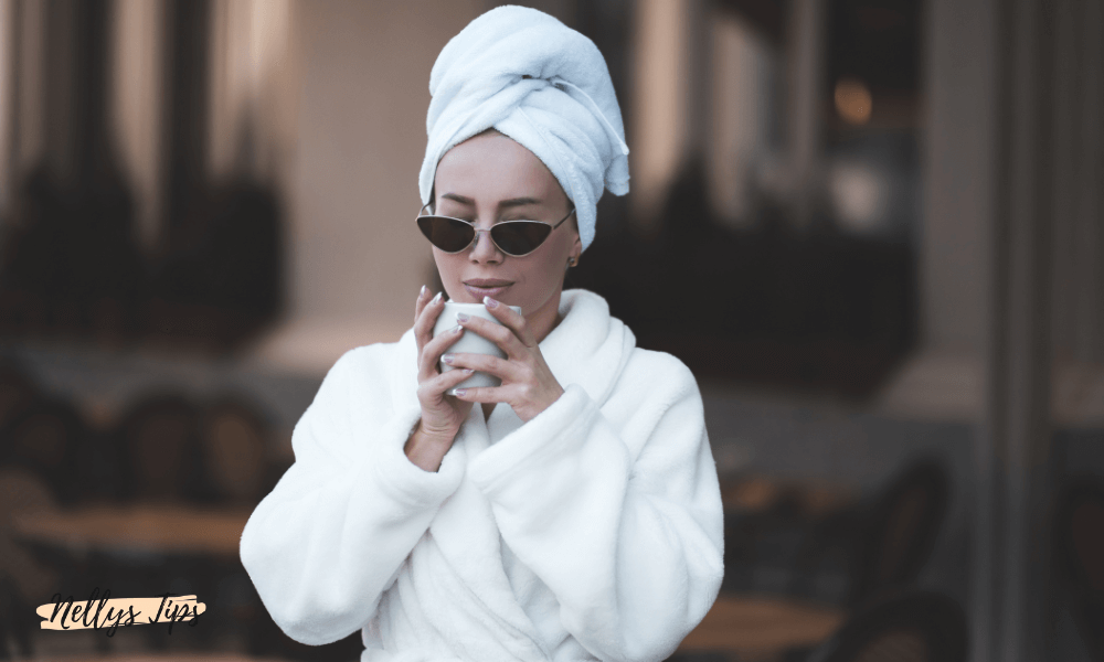 Kvinna i vit badrock och handduksturban med solglasögon och kaffekopp, lyxig spa-känsla