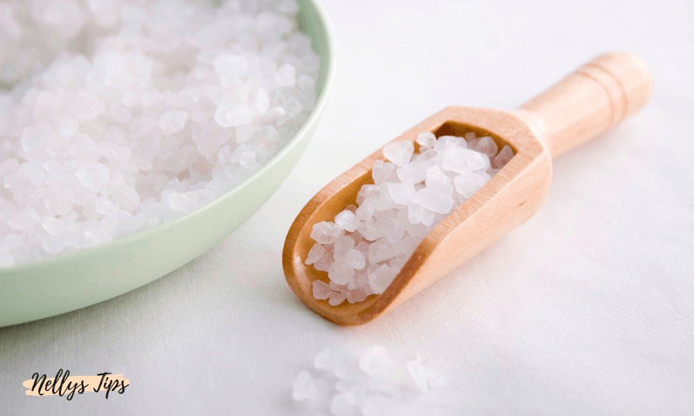 Skål med grovt badsalt och träskopa redo att användas för avslappnande badritualer.