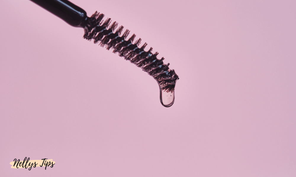 Närbild på mascara-liknande borste med klar ögonbrynsgel mot rosa bakgrund.