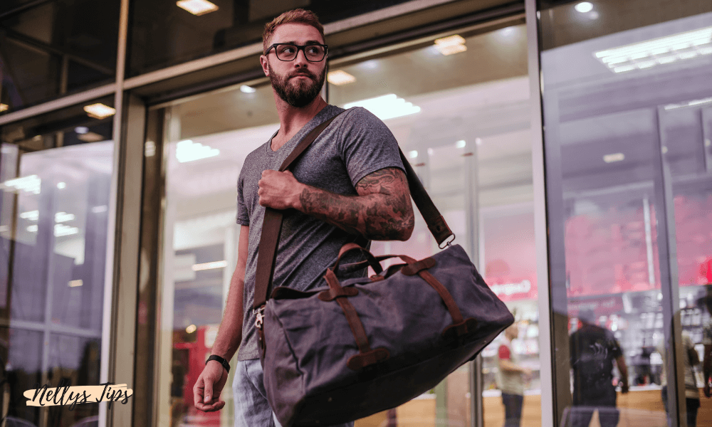 Man bär sportväska med axelrem utanför glasfasad butik.