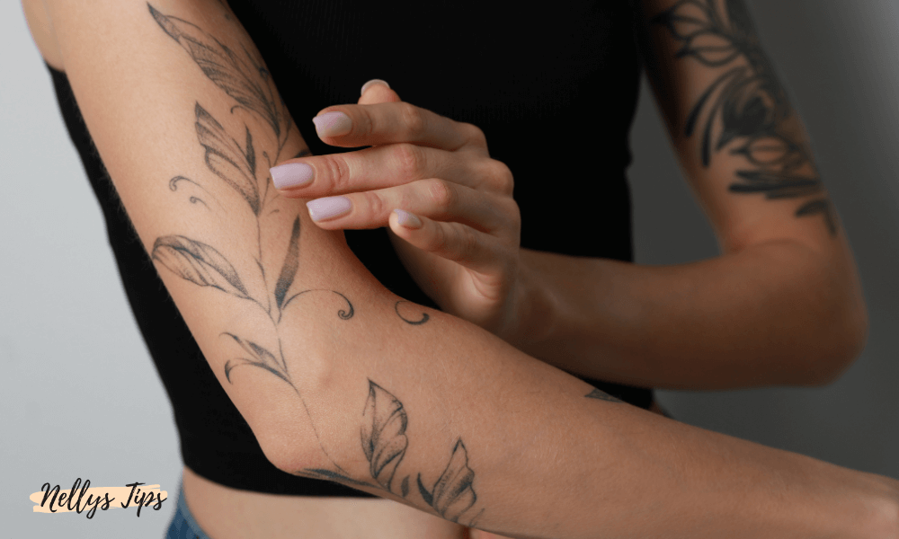 Person applicerar tatueringskräm på armen med svartvit bladtatuering