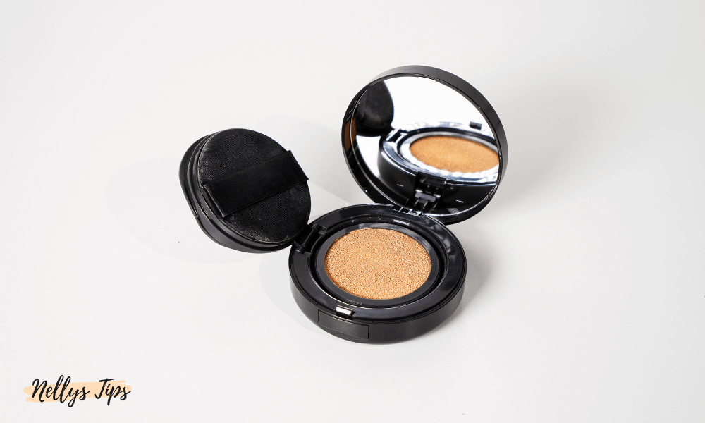 Svart compact med cushion foundation, spegel och svampapplikator i fokus.