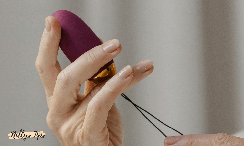 Hand som håller i en liten trådlös vibrator i lila färg med gulddetaljer