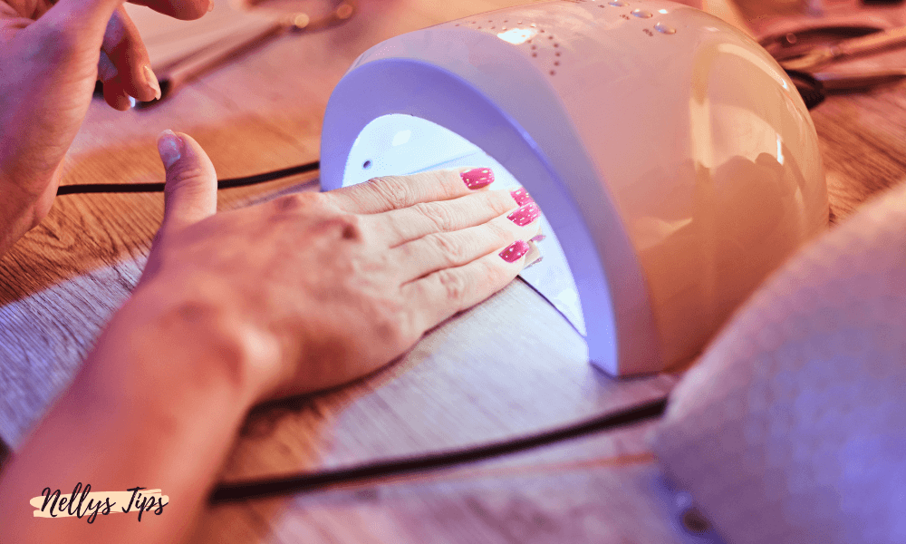 Hand under UV-lampa för härdning av gelnaglar – steg i hemmamanikyr