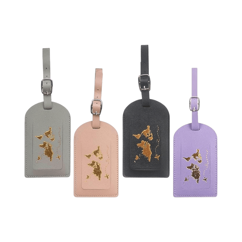 Fyra stilrena bagagelappar i grå, rosa, svart och lila med världskarta i guld.