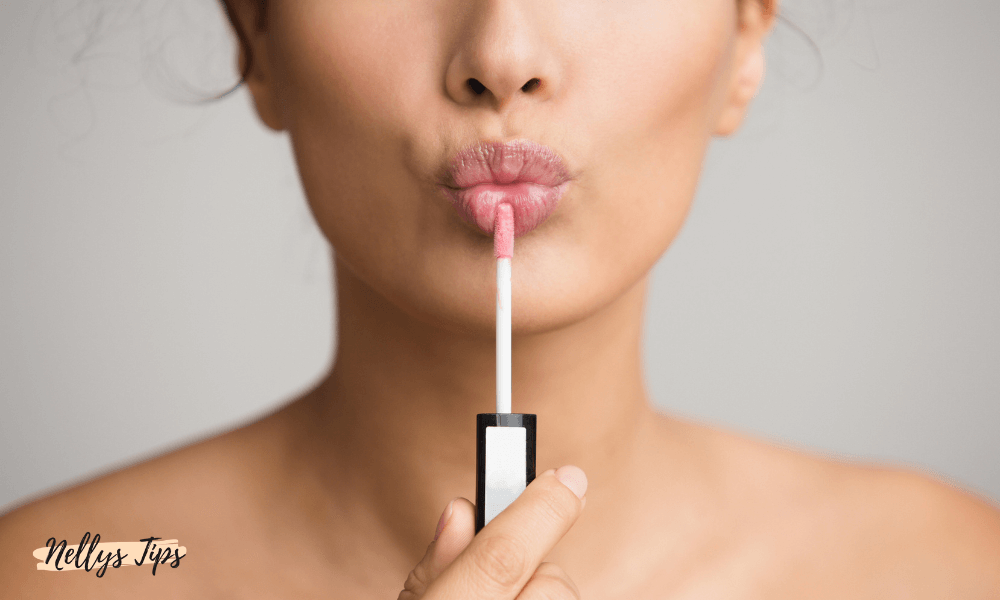 Kvinna applicerar rosa lip plumper med applikator på läpparna.
