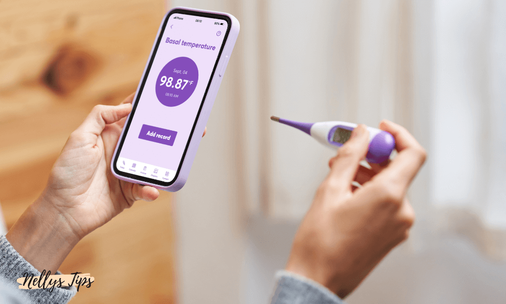 Person mäter basaltemperatur med digital termometer och loggar värdet i fertilitetsapp på mobilen.
