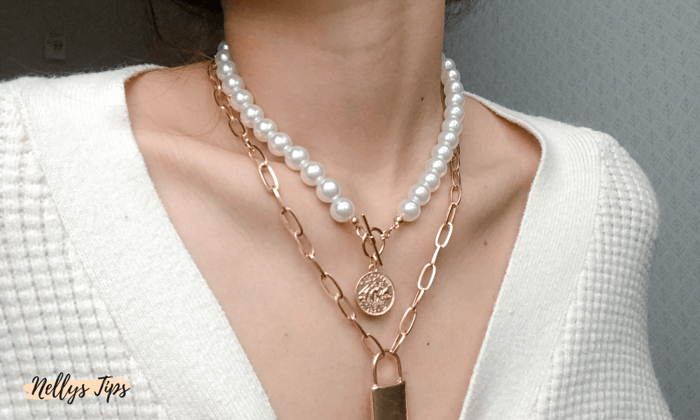 Trendig lager på lager-styling med pärlhalsband och guldhalsband med berlocker.