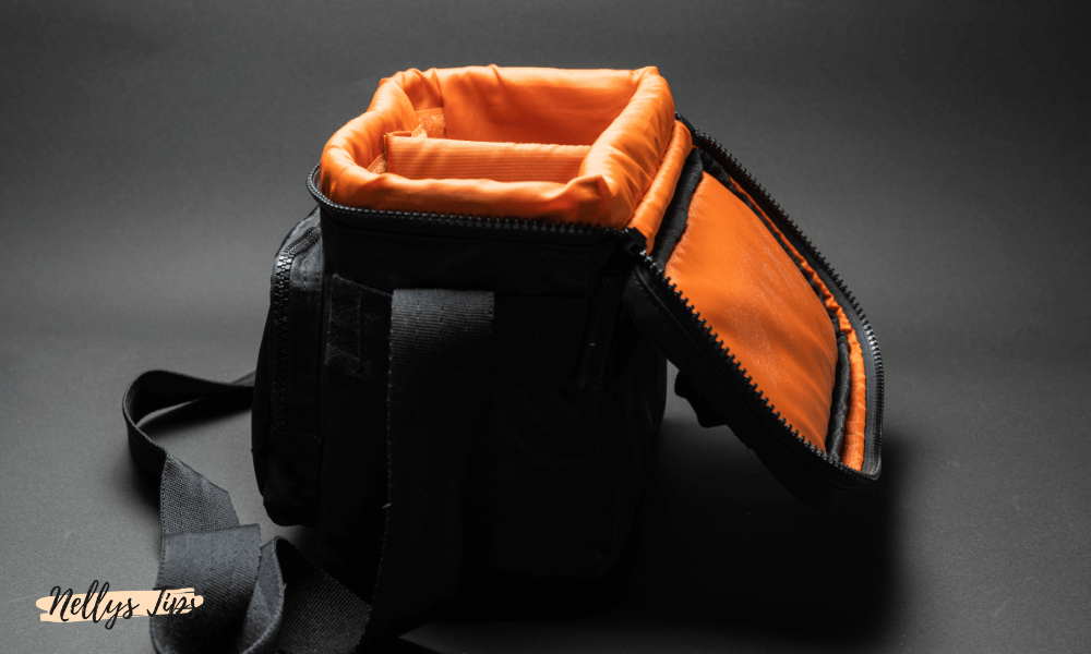 Kompakt kameraväska med orange vadderad insida och öppet lock för enkel tillgång