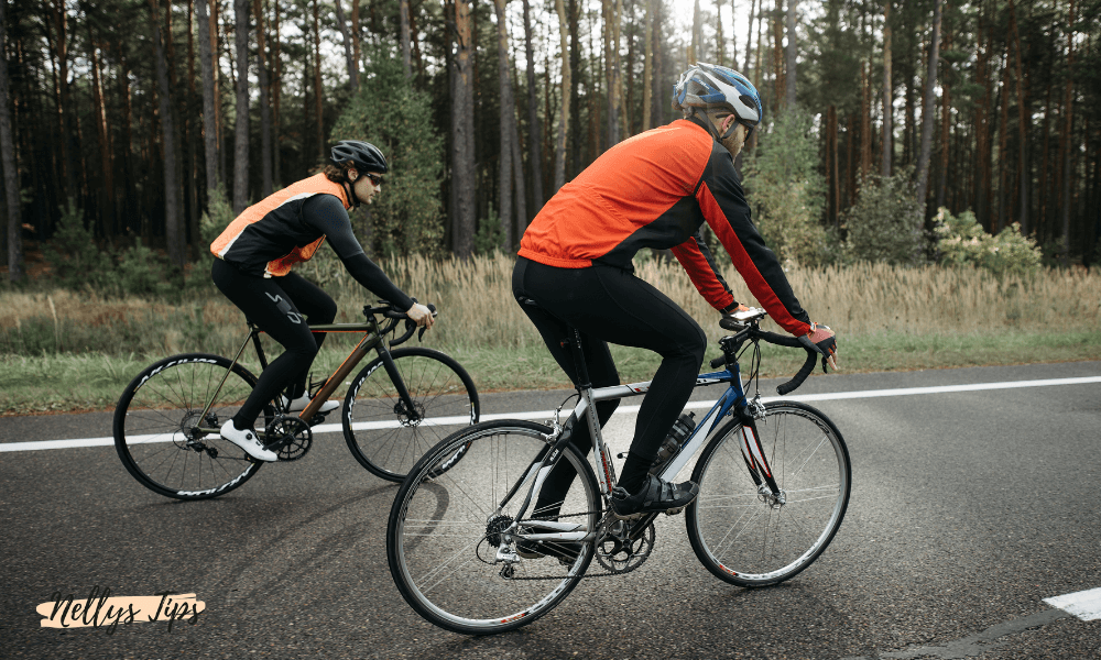 Två cyklister på landsväg iförda reflexvästar och cykelhjälmar, visar säker cykling i trafik.