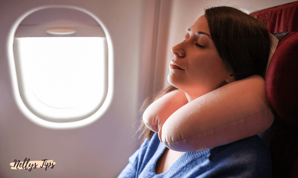 Kvinna som sover bekvämt med U-formad resekudde runt nacken under flygresa.