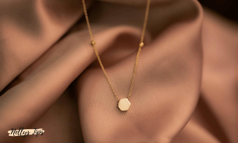 Minimalistiskt guldhalsband med liten hexagonformad berlock i modern design.