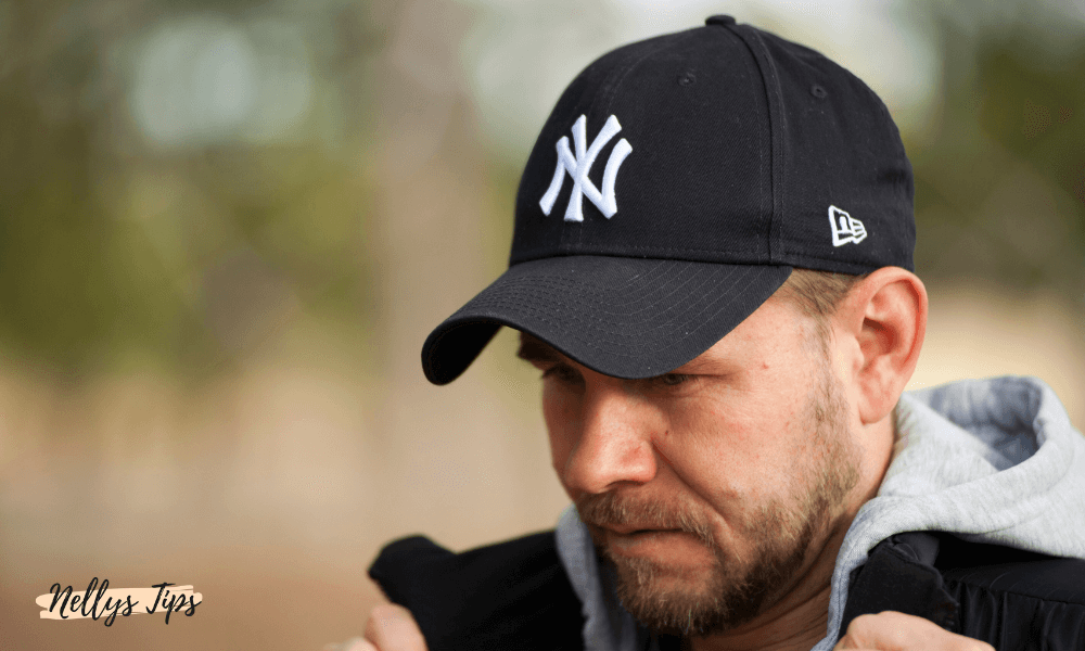 Svart New York Yankees-keps med vit broderad logga, buren av man i sportig outfit.
