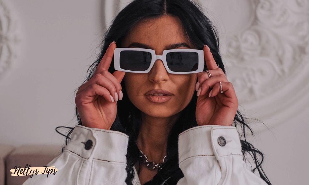 Kvinna bär vita rektangulära solglasögon med svarta glas