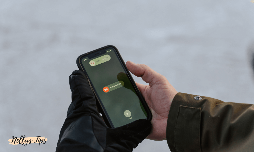 Person med ena handen i svart handske använder nöd-SOS-funktionen på iPhone.