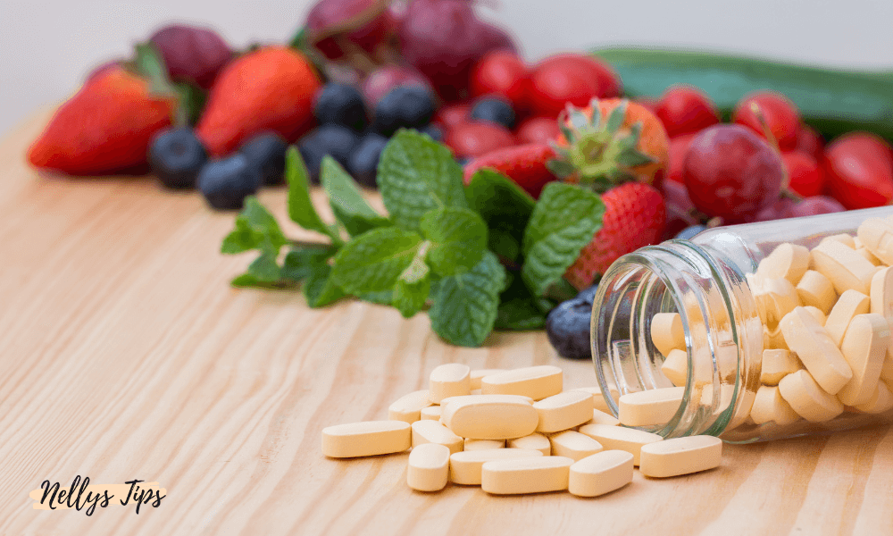 Glasburk med multivitamintabletter på träbord tillsammans med färska bär och grönsaker.