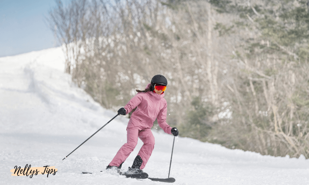 Kvinna åker skidor i rosa skidset med hjälm och goggles – aktiv vintersport i full fart.